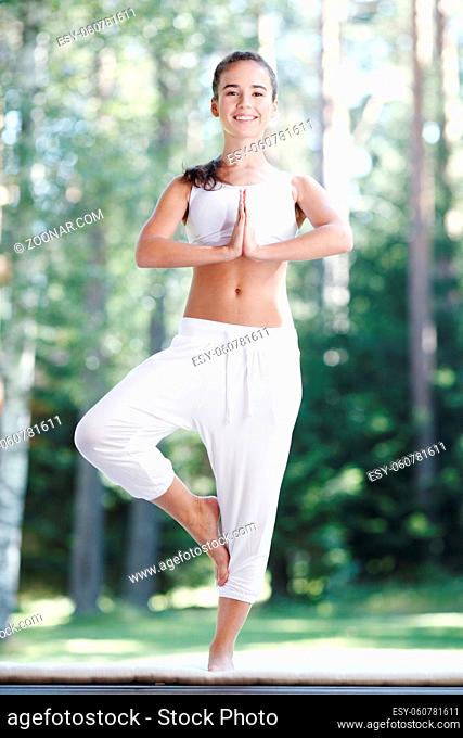 Pretty young woman doing yoga exercise in the park