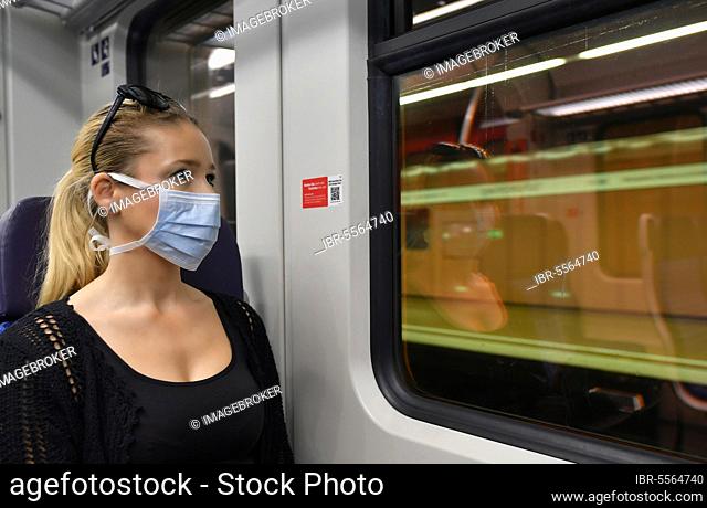Woman with a respirator mask, sitting in train, reflected in S-Bahn, corona crisis, Stuttgart, Baden-Württemberg, Germany, Europe