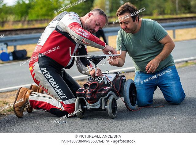 29 July 2018, Germany, Darmstadt: Dirk Auer (L), extreme athlete, and Aliatdin Sen, long-time friend and assistant, assemble the steering handles