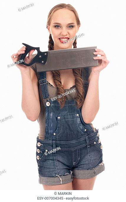 Young playful woman in jeans coverall holding hand saw