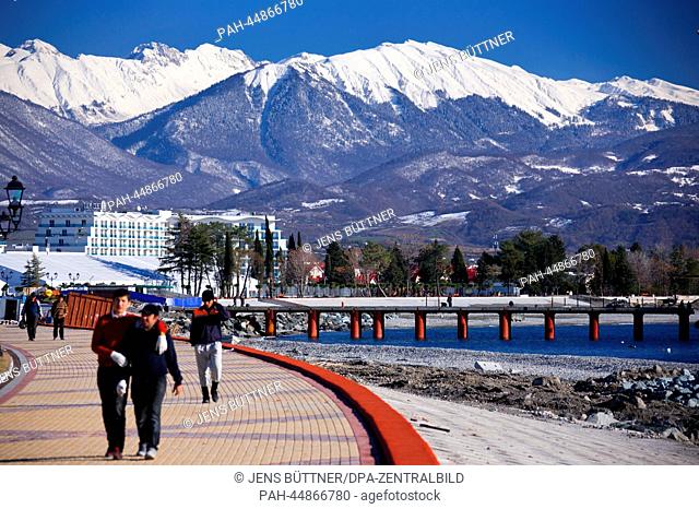 Construction workers walk along the beach promenade in front of the Caucasus Mountains in Sochi, Russia, 17 December 2013