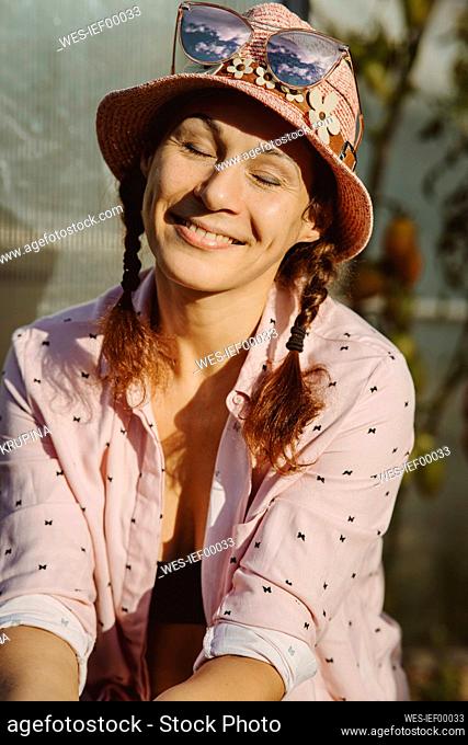 Smiling woman wearing hat sitting with eyes closed
