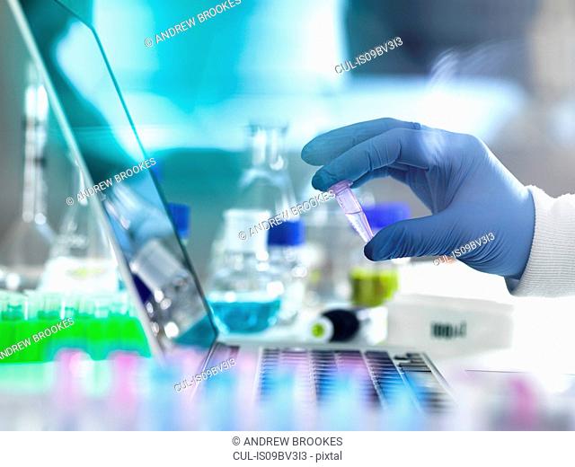Research experiment, scientist examining vial containing sample used in biomedical, DNA, biotechnology, analytical chemistry and pharmaceutical research