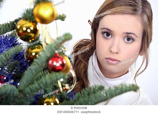 woman posing next to a Christmas tree