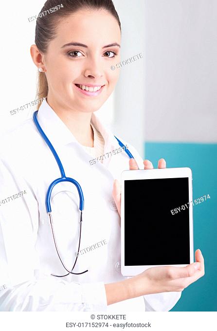 Portrait of a beautiful young female doctor in scrubs with stethoscope around neck holding digital tablet