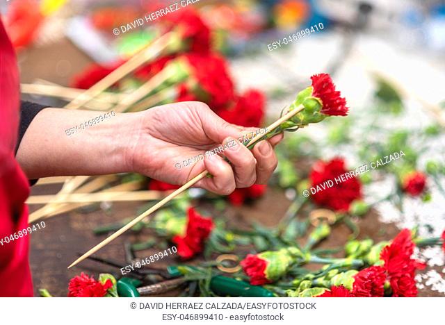 Close up of female florist creating beautiful red carnation bouquet at flower shop