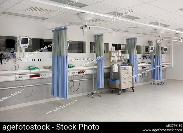 Recovery room outside the operating theatre in a hospital. Drapes, blue curtains around patient bays