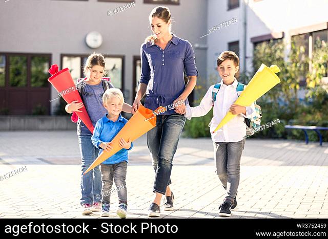 Mum and children with paper funnels for candy after first day at school