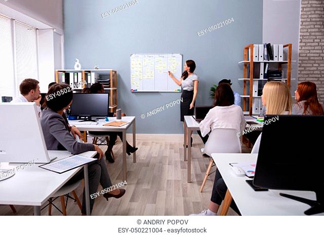Smiling Young Businesswoman Giving Presentation To Her Executives At Workplace