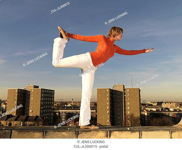 Woman balancing on roof terrace