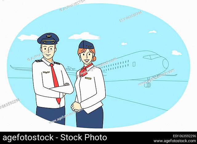 Smiling pilot and stewardess posing together near aircraft. Happy airplane crew members in uniform near plane ready for flight in airport