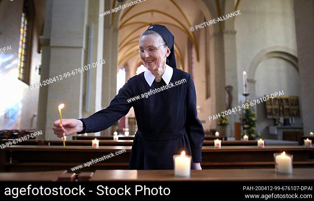 12 April 2020, Saxony-Anhalt, Magdeburg: Sister Therese lights candles that were placed in the place of the faithful. Because of the measures taken against the...