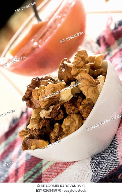 Apple compote with dried fruits in the cup on wooden table with decorative wallnuts