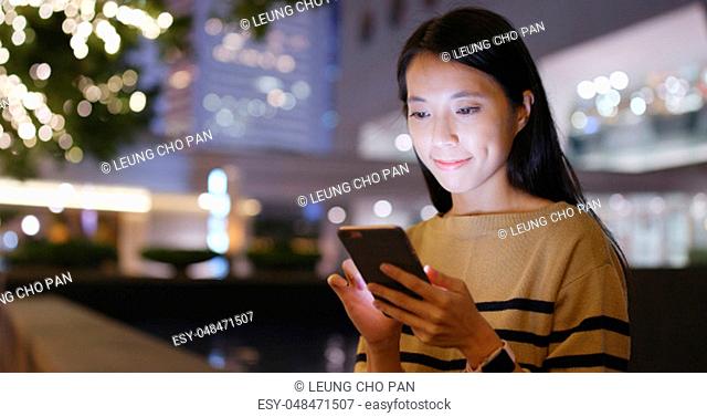 Woman looking at cellphone with Christmas decoration light of the background