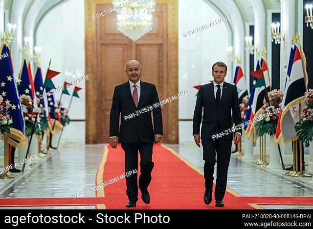 28 August 2021, Iraq, Baghdad: Iraqi President Barham Salih (L), welcomes French President Emmanuel Macron at the Baghdad's Presidential Palace ahead of their...