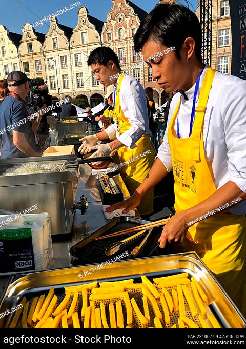 07 October 2023, France, Arras: Restaurateurs Chikara Yoshitomi (l) and Sugio Yamaguchi (r) prepare French fries. Dozens of French fry restaurateurs compete in...