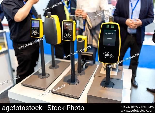 10 May 2022, Baden-Wuerttemberg, Rheinstetten: Devices for digital tickets stand in a hall at Messe Karlsruhe while people can be seen behind them