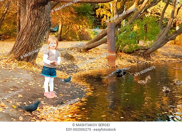 The girl feeds ducks and pigeons