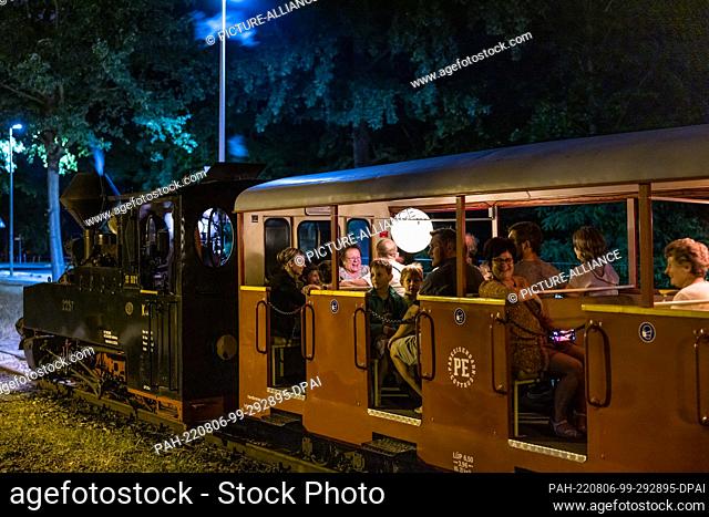 05 August 2022, Brandenburg, Cottbus: A train leaves a station during the so-called light rides of the Cottbus park railroad
