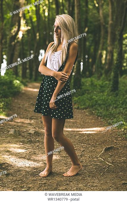 Unsmiling gorgeous blonde standing on forest track