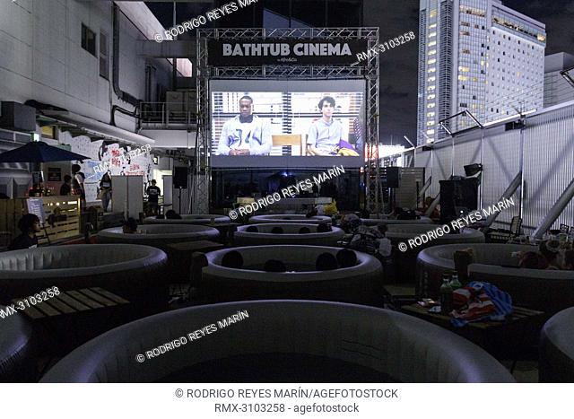 August 17, 2018, Tokyo, Japan - People enjoy a movie sitting in small inflatable water pools on the rooftop of the revamped MAGNET by Shibuya109 building in...