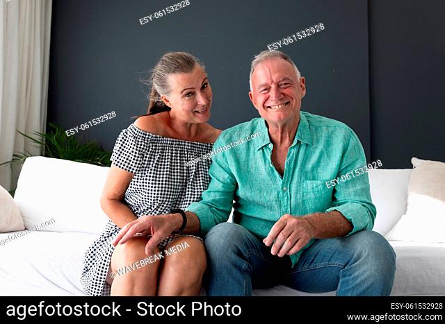 Happy caucasian senior couple in living room, on couch making video call, talking and smiling