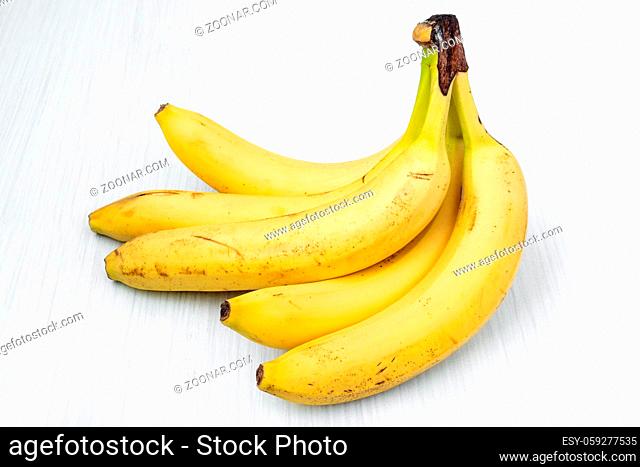 Sweet bananas bunch lying on white wooden table