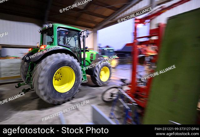 21 December 2023, Lower Saxony, Hanover: A farmer in the Hanover region drives his tractor out of a vehicle shed. Recently