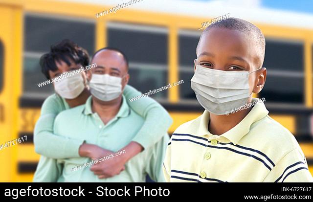 Young african american student and parents near school bus wearing medical face masks during coronavirus pandemic