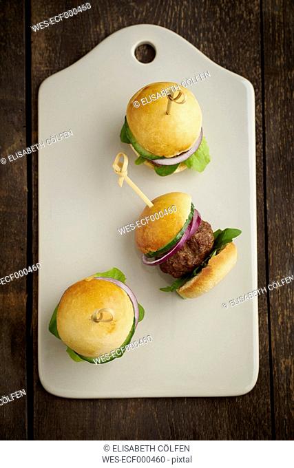 Mini-Burger with mincemeat, salad and red onions on white chopping board