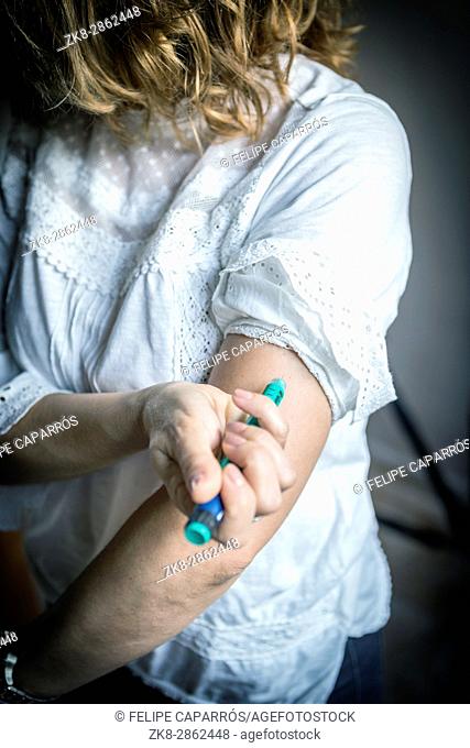 medicine diabetes glycemia health care and people concept - close up of woman with syringe making insulin injection to himself at home