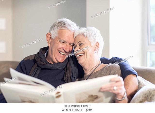 Senior couple sitting on a couch with photo album