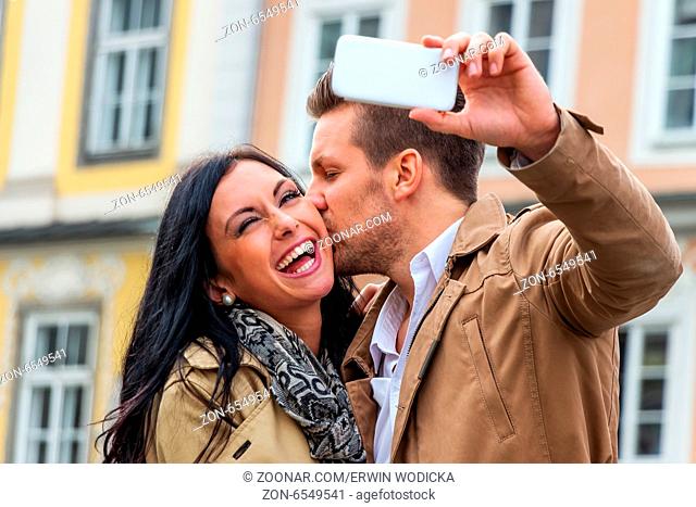 Ein junges Paar macht ein Selbstporträt mit einem Handy. Selfies sind in