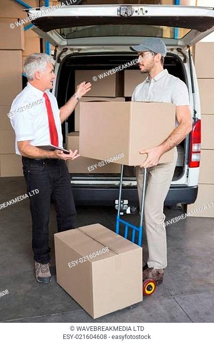 Warehouse manager and delivery driver talking beside van