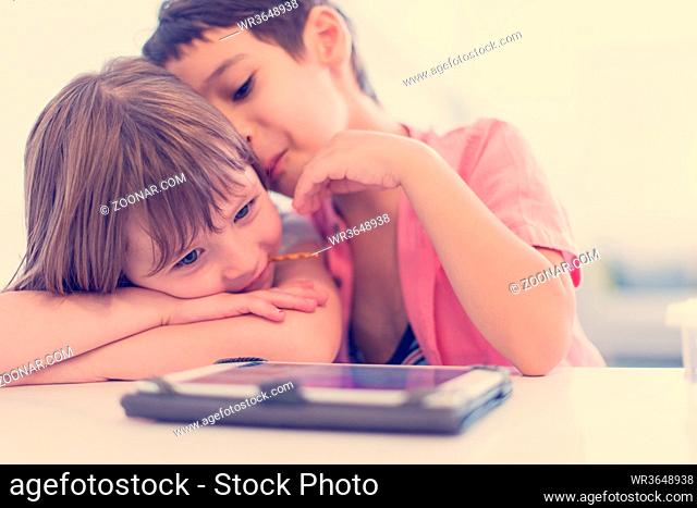 cute little brother and sister having fun at home childrends playing games on tablet computer