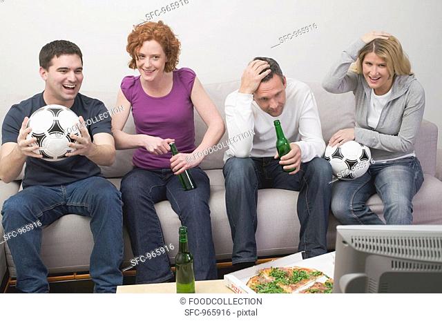 Friends in front of TV with footballs, beer and pizza