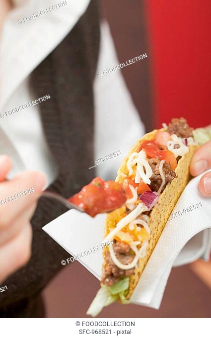 Woman putting sauce on mince taco