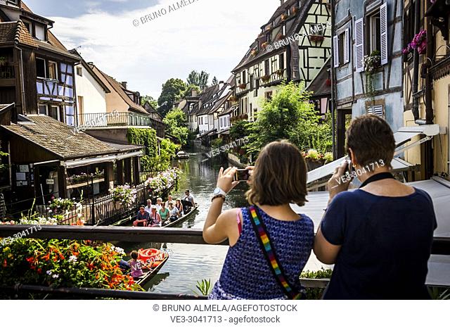 Taking pictures of tourists boat along channel at Little Venice in medieval town of Colmar, Alsace (department of Haut-Rhin, region of Grand Est, France)