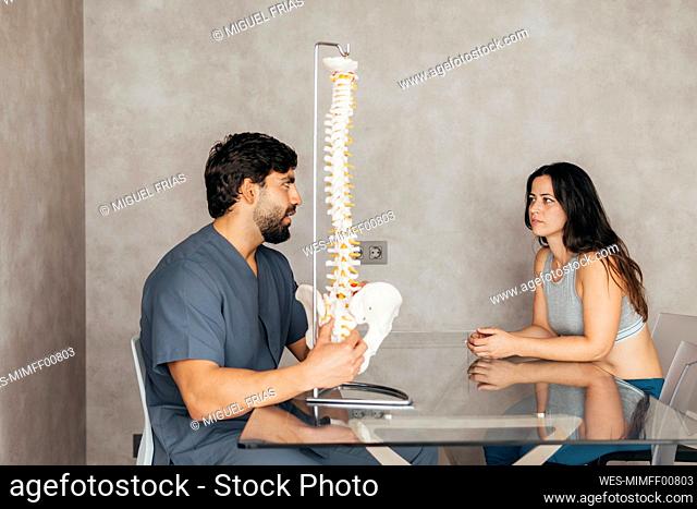 Physiotherapist explaining human spine anatomy to woman