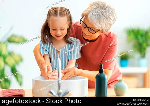 A cute little girl and her grandmother are washing their hands. Protection against infections and viruses