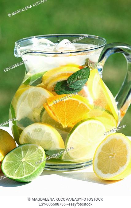 Jug with fresh fruit lemonade in a garden
