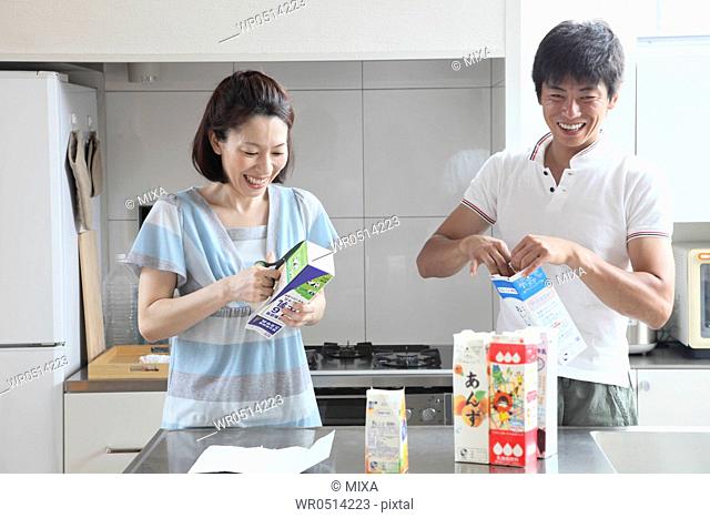 Mid adult couple opening milk carton for recycle