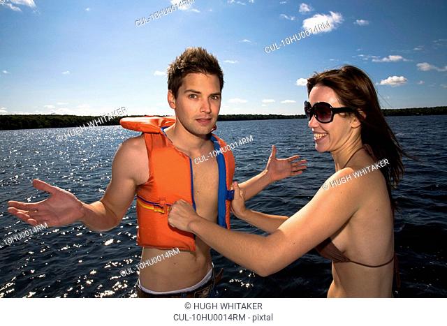 Woman helping man into small lifejacket