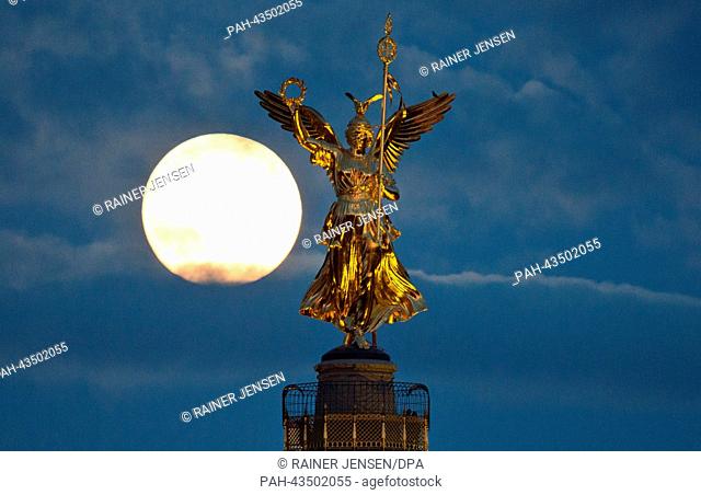 The moon seems to be right next to the statue of Victoria on top of the Berlin Victory Column in Berlin, Germany, 18 October 2013