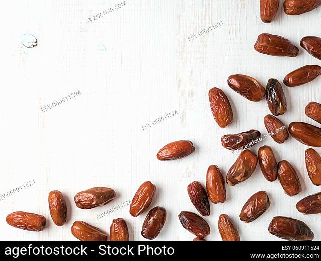 Sweet dried dates on white wooden background. Dried dates with copy space. Sugar free alternatives concept. One edge image with space for text