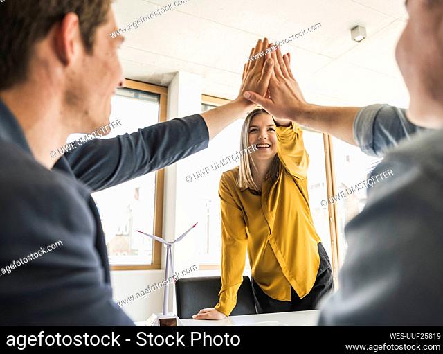 Happy business team high fiving in office