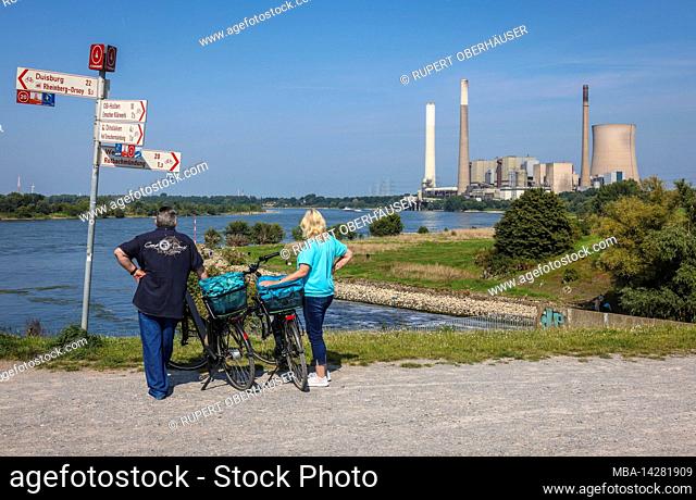 Dinslaken, North Rhine-Westphalia, Germany - Emschermuendung into the Rhine. Cyclists take a break at the viewpoint. On the right the decommissioned STEAG...