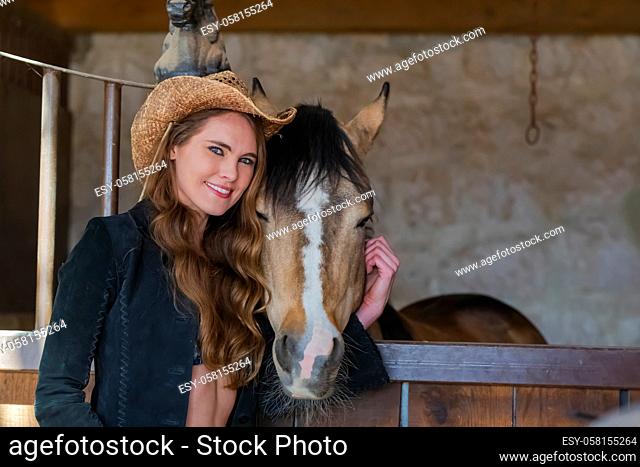 A gorgeous Hispanic Brunette model poses with a horse outdoors in a Mexican stable