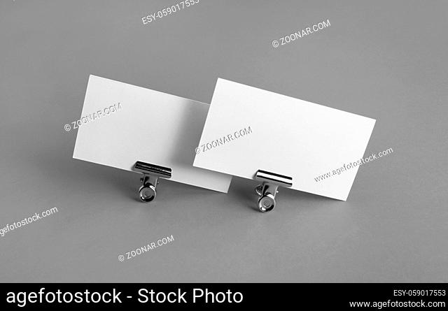Blank white business cards and metal binder clips on gray background. Mockup for branding identity