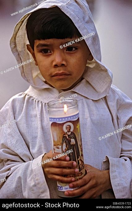 A boy holds a candle during a Good Friday reenactment of the Stations of the Cross at St. Anthony's Catholic Church in Virginia